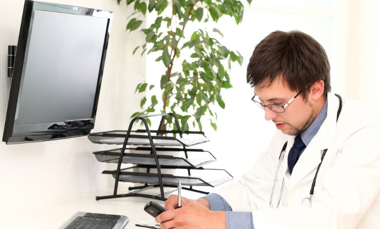 a doctor on the table in front of screen seeing reason of denied claims in dental billing