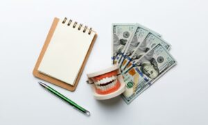 Cash with teeth near with dental billing pad with a pen