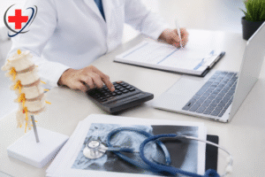 Medical billing professional reviewing pain management billing documents with a calculator, laptop, and spine model, featuring The Medicators logo.